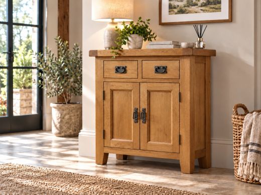 Country Oak 80cm fully assembled sideboard with two drawers, two panelled cupboard doors and dark metal drop handles in a sunlit hallway