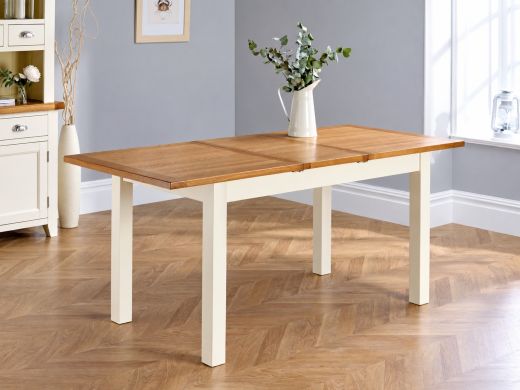 Country Oak cream painted butterfly extending dining table fully extended with an oak top and eucalyptus in a white jug in a grey dining room with herringbone flooring