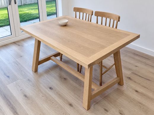 Doveridge 140cm whitewash limed oak trestle dining table with two matching chairs beside white garden doors