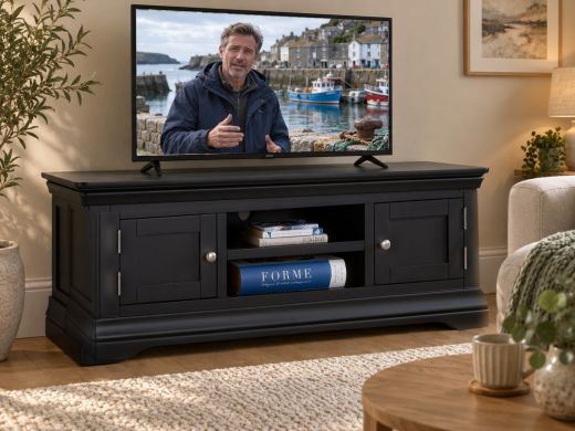 Toulouse black painted large TV unit with two doors and a central shelf in a warm living room with a television