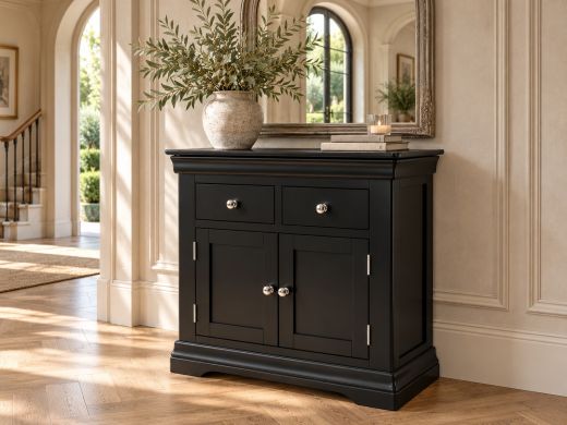 Toulouse black painted small sideboard beneath an ornate mirror in a bright country hallway with oak herringbone flooring