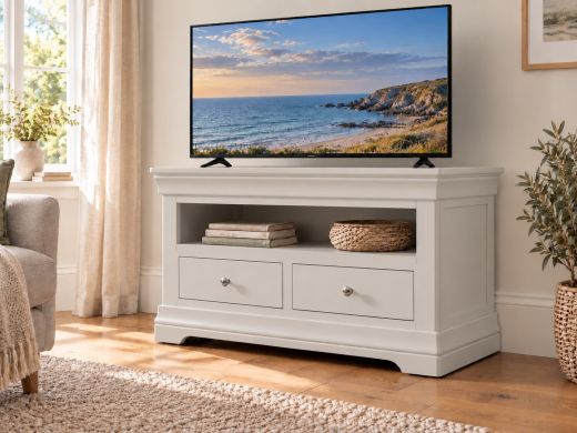 Toulouse grey painted two-drawer TV unit with an open shelf in a bright living room beneath a television showing a coastal scene