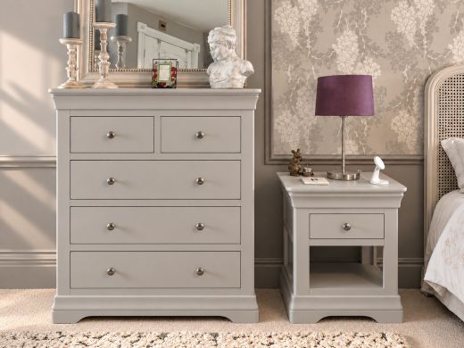 Toulouse grey painted one drawer bedside table with an open shelf beside the matching 2 over 3 chest of drawers in a bedroom with floral wallpaper and a purple lamp