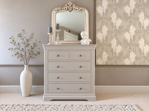 Toulouse grey painted 2 over 3 chest of drawers beneath an ornate mirror, styled with candles, a classical bust and a floor vase with leafy branches