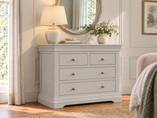 Toulouse grey painted 2 over 2 chest of drawers with chrome knobs, styled with a ceramic lamp and flowers in an elegant bedroom