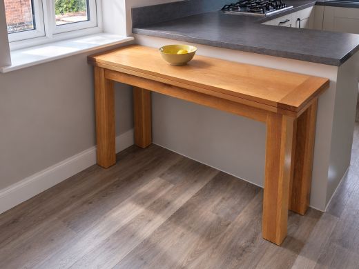 Lichfield 140cm flip top oak console table in its closed position beside a kitchen window