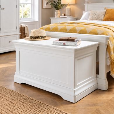 Toulouse White Painted Storage Blanket Box Ottoman in a bright bedroom, styled at the foot of a bed with a hat and books