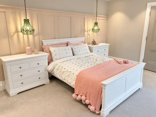 Toulouse white painted double bed frame with panelled headboard and footboard in a bedroom with pink bedding