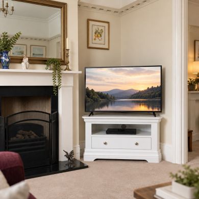 Toulouse White Painted Assembled Corner TV Unit with Drawer beside a traditional fireplace in an elegant neutral living room