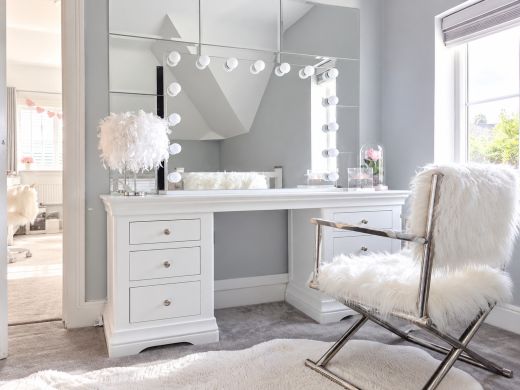 Toulouse white painted double pedestal dressing table with chrome knobs, vanity mirror and fluffy chair in a bright dressing room
