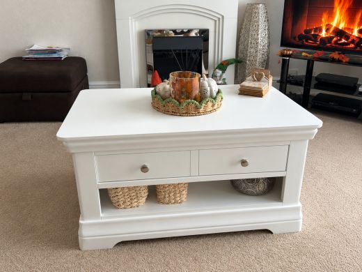 Toulouse brilliant white painted coffee table with single drawer, chrome knobs and open storage shelf, styled with autumn decorations in a living room with a white fireplace