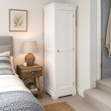 Toulouse white painted narrow tall storage cupboard in a bright modern bedroom with classic panelled door and metal knob