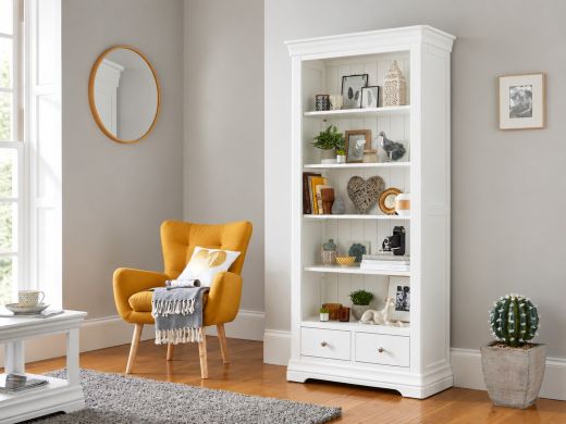 Toulouse white painted tall bookcase with four shelves and two drawers in a living room beside a mustard armchair