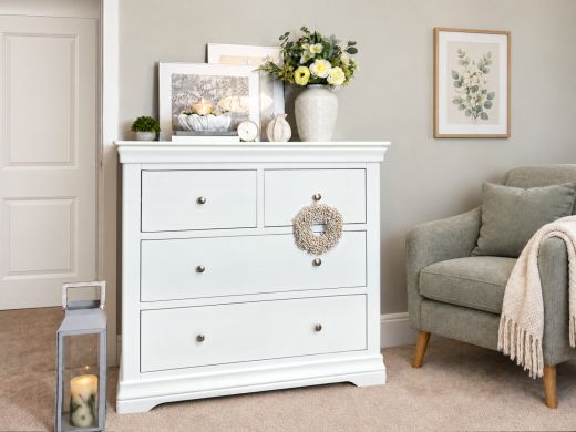 Toulouse White Painted Grande 2 over 2 chest of drawers with chrome knobs, flowers and a decorative wreath in a styled bedroom