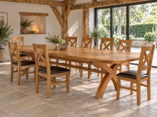 Country Oak 340cm extending dining table with rounded corners and eight cross-back chairs in an oak-beamed room overlooking a stone-walled garden