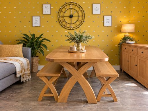 Country Oak 180cm cross-leg dining table with rounded corners and two oak benches, styled with flowers in a warm mustard dining room