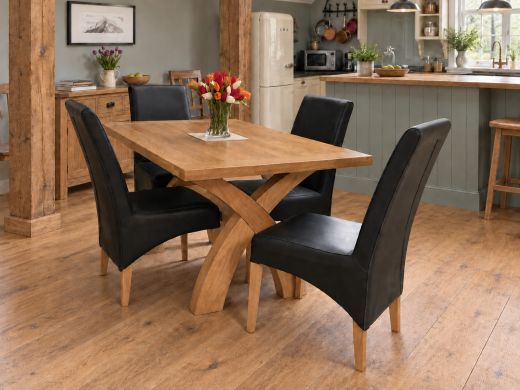 Country Oak 140cm cross leg dining table with four black dining chairs and tulips in a farmhouse kitchen with oak beams